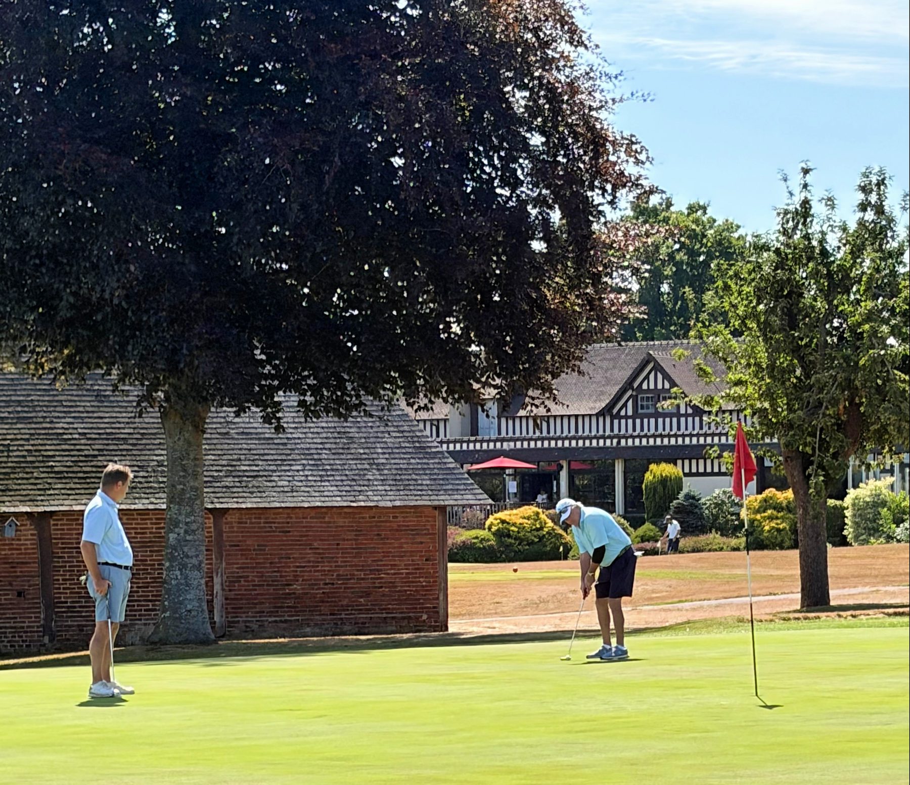Golfers on the practice green at Golf Barrière de Deauville with the clubhouse behind